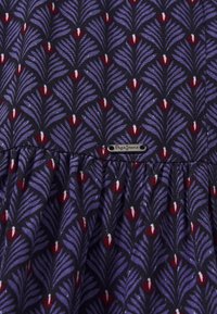 Der Stoff mit Blumenmuster hat einen dunklen Hintergrund und Akzente in Lila, Rot und Weiß. Er enthält ein kleines Metall-Logo-Tag in der Nähe der Naht.