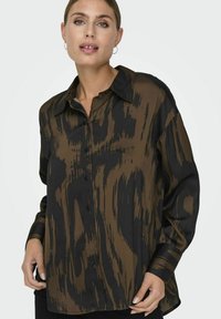 Blusa a maniche lunghe con un motivo astratto marrone e nero, dotata di colletto classico e chiusura con bottoni, realizzata in tessuto leggero e morbido.