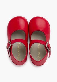 Zapatos Mary Jane de cuero rojo con punta redonda, bordes festoneados, correa con hebilla y textura suave. Logotipo dorado en la plantilla.