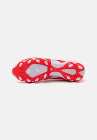 Red and white multi-ground soccer cleat with a textured upper, cushioned sole, and prominent circular studs for enhanced grip.