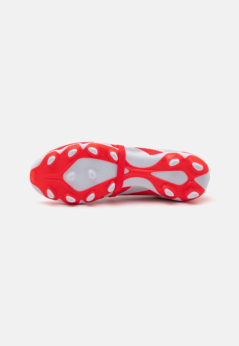 Chaussures de football multi-terrain rouges et blanches avec une tige texturée, une semelle rembourrée et de grands crampons ronds pour une meilleure adhérence.