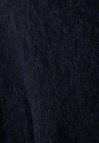 Tissu feutré bleu marine avec une texture dense et douce, présentant une surface floue légèrement inégale et sans motifs ni accents visibles.