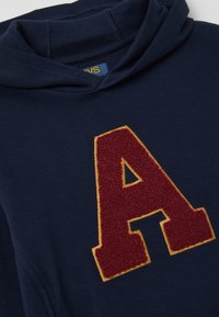 Marineblauwe hoodie met een textuur maroon 'A' embleem omrand met gele stiksels. Beschikt over een capuchon en een ribgebreide halslijn. Zachte jersey stof.