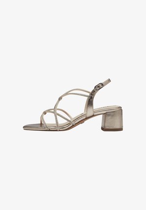 Metallic gold block-heeled sandals with crisscross straps. Smooth texture, adjustable ankle strap, and subtle embellishments on straps.