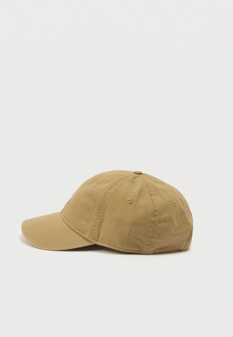 Brun bomuld baseballkasket med sammen syede paneler og ventilationsøjne, vist på en ensartet lys baggrund med front mod venstre.
