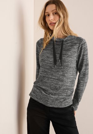 Gråmelerad hoodie i texturerat tyg, med dragsko i huvan, långa ärmar och avslappnad passform, parat med svarta byxor.