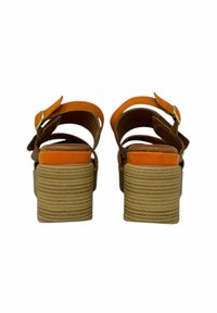 Sandali con tacco alti marroni e arancioni con una piattaforma testurizzata e cinturino alla caviglia regolabile. Presentano una tomaia in pelle liscia e una soletta in sughero.