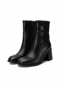 Botines de cuero negro con un acabado suave, cremallera lateral y tacón cuadrado, con puntera redondeada y detalles de costura a lo largo de los bordes.