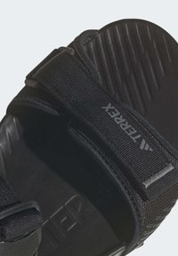 Czarne sportowe sandały z regulowanymi paskami, teksturowaną wkładką i detalami z logo. Wykonane z trwałych materiałów dla komfortu i wsparcia.