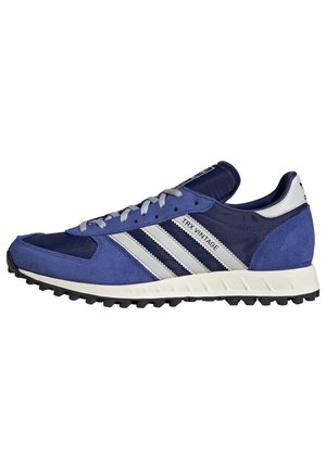 Blaue und marineblaue Adidas TRX Vintage Sneaker mit weißen Streifen, grauen Schnürsenkeln und einer strukturierten schwarzen Außensohle.