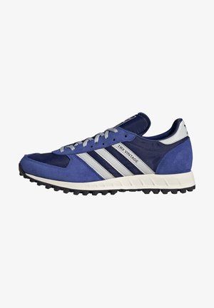 Baskets Adidas TRX Vintage bleu et marine avec des bandes blanches, des lacets gris et une semelle extérieure noire texturée.