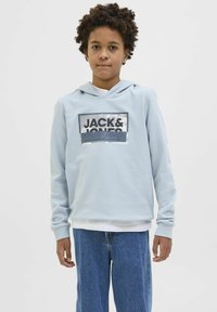 Svijetloplava dukserica s kapuljačom i prednjim printom "JACK & JONES", u kombinaciji s plavim trapericama. Mekani materijal, opušteni kroj, rebraste manžete.