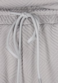Ljusgrått tyg med ett strukturerat fiskbensmönster. Elastisk midja med snörning i matchande ljusgrå färg.