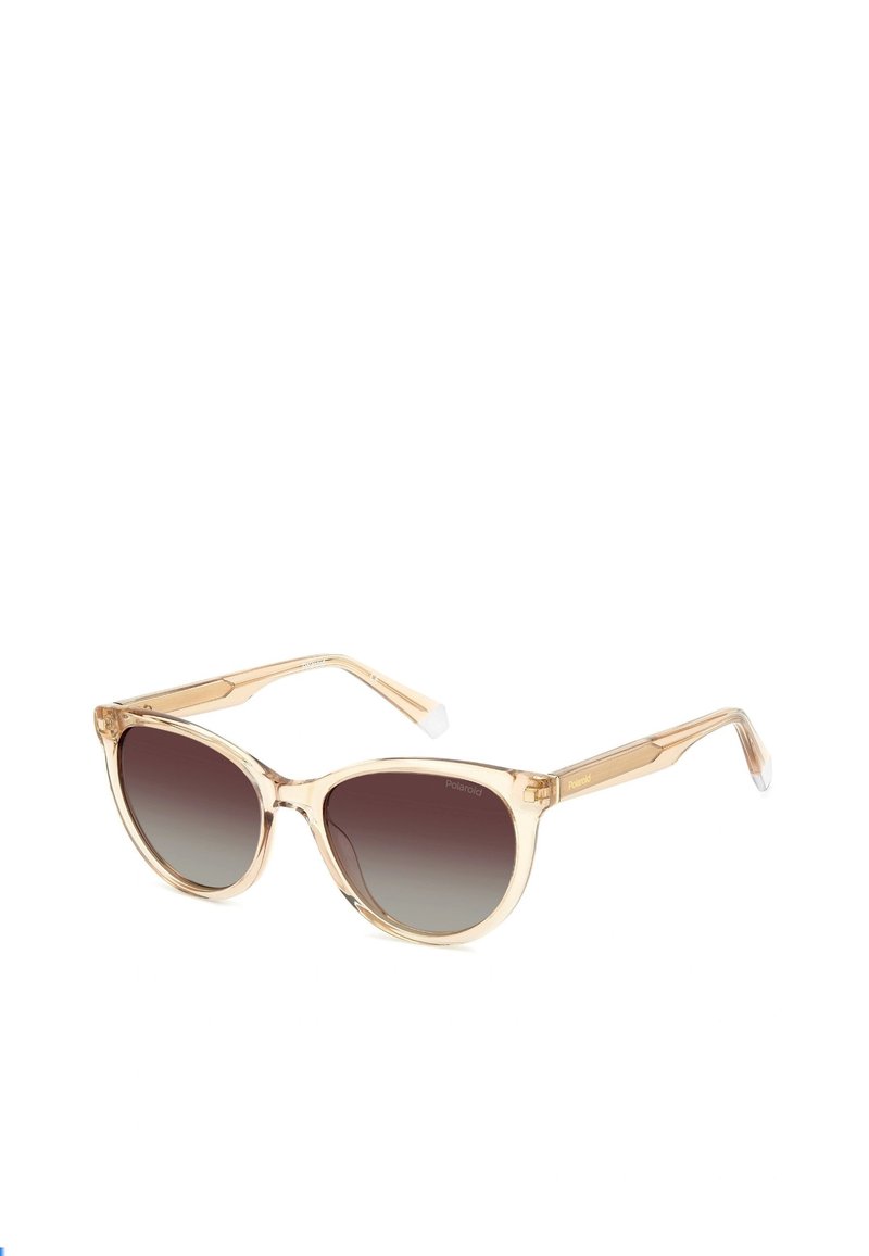 Occhiali da sole con montatura trasparente beige, lenti marroni sfumate, forma a occhio di gatto e aste sottili con un discreto accento di branding.