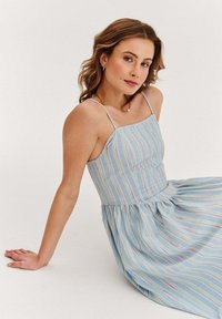 Jasnoniebieska sukienka w cienkie paski w pastelowych kolorach, z dopasowaną górą, regulowanymi ramiączkami i rozkloszowaną spódnicą.
