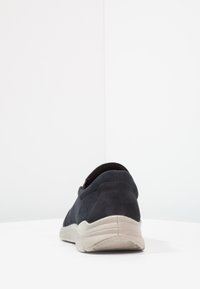 Sötétkék velúr sneaker sima textúrával, lekerekített formával és világosszürke gumitalppal. Könnyen felvehető slip-on kialakítás jellemzi.
