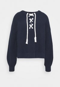 Maglione lavorato a maglia blu navy con un design cropped, scollatura rotonda e dettaglio bianco con lacci sul davanti che presenta dei pon-pon alle estremità.
