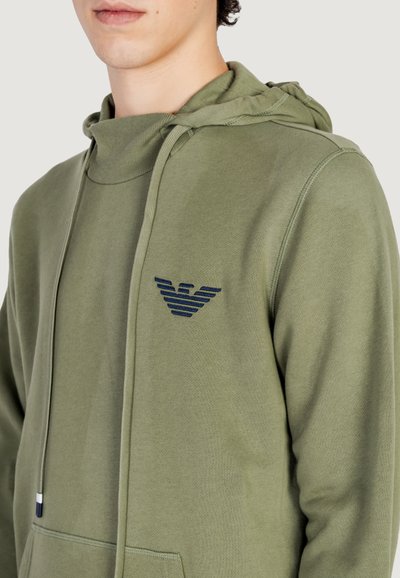 Sweat à capuche vert Olive avec un col montant, des cordons de serrage et une poche avant. Présente un logo brodé bleu marine sur la poitrine. Tissu doux et texturé.