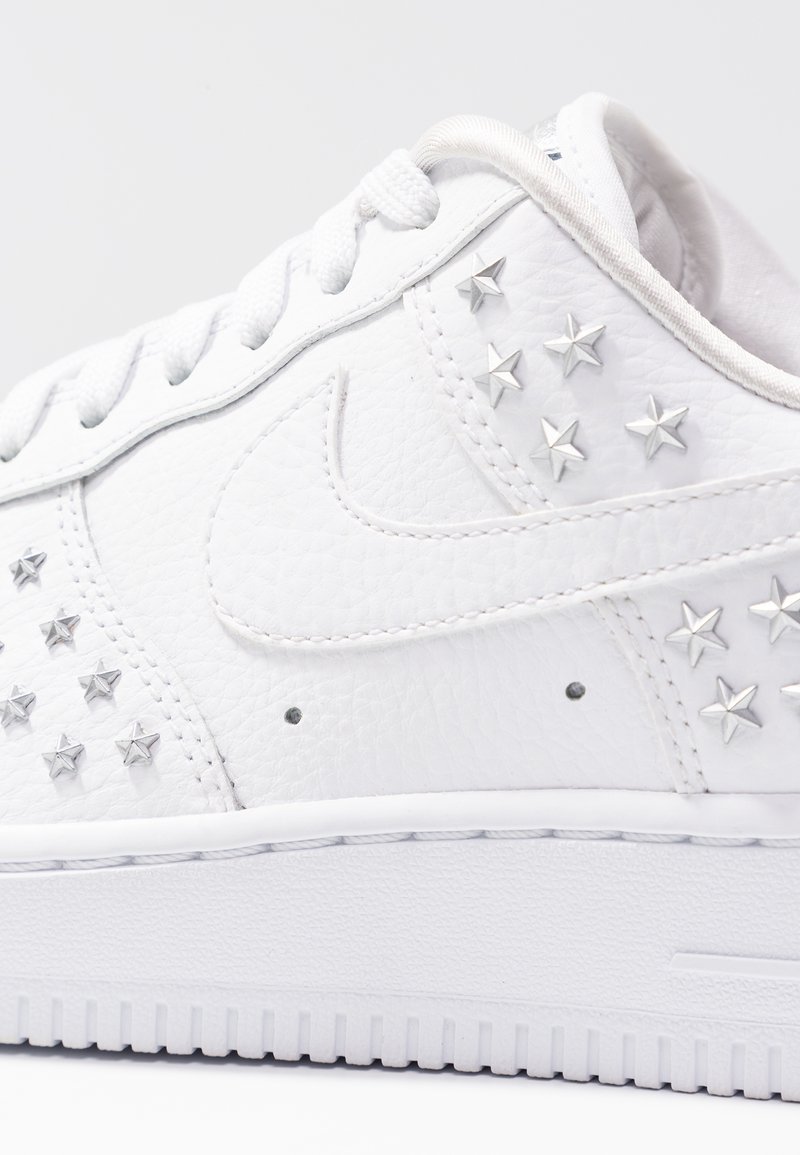 Weiße Leder-Sneaker mit silbernen Sternverzierungen, Schnürdesign, strukturierter Oberfläche und weißer Gummisohle.