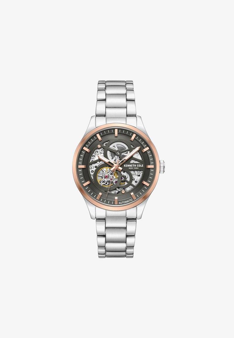 Automatinis laikrodis su nerūdijančio plieno juosta, pilku ciferblatu ir rožių auksu akcentais. Yra skeleto dizainas ir tikslūs valandų žymenys.
