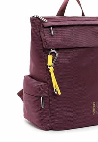 Burgundowa plecak z teksturowanym materiałem, srebrnymi akcesoriami i żółtym uchwytm do zamka. Posiada przednią kieszeń oraz boczną kieszonkę do przechowywania.
