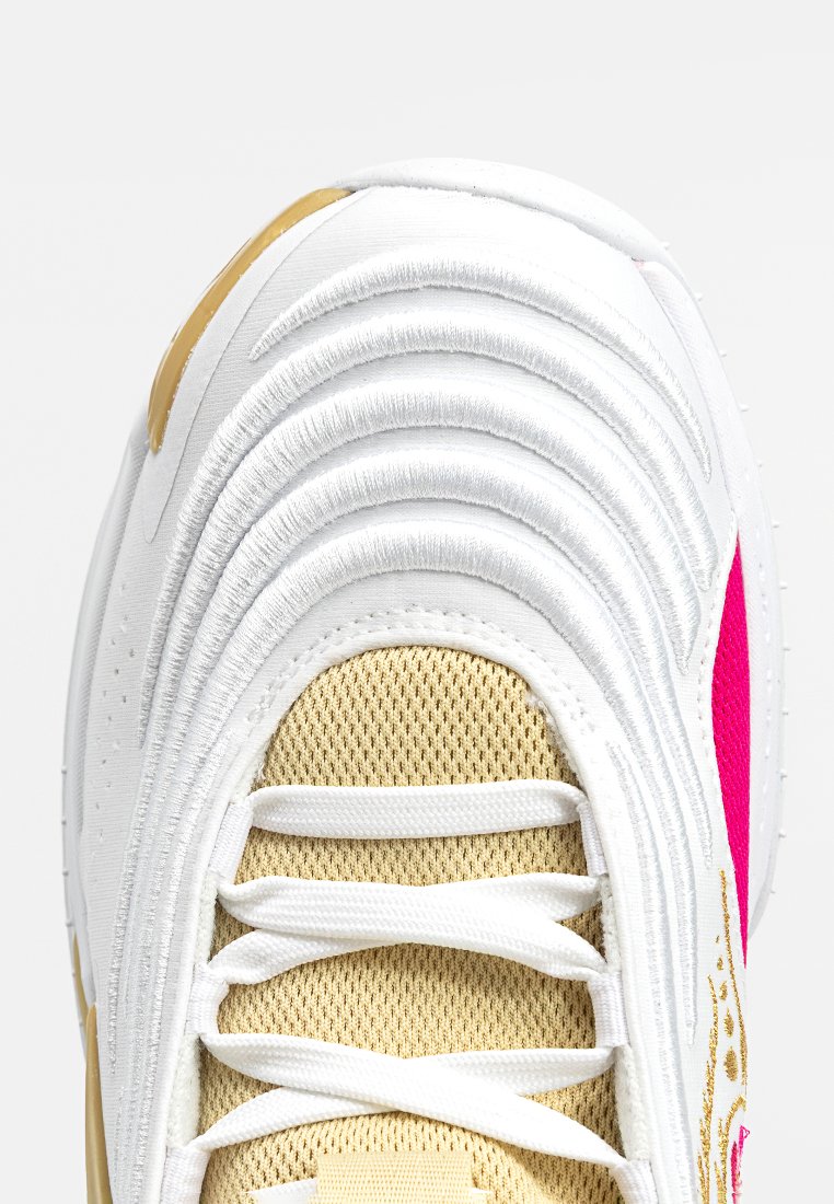Basket blanche avec un design texturé ondulé, une languette en mesh beige, des lacets blancs et un accent rose sur le côté.