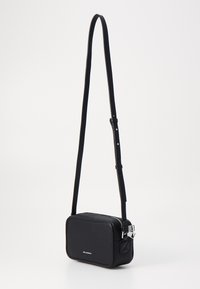 Sac en bandoulière noir en cuir texturé, de forme rectangulaire, avec une sangle réglable et un matériel en métal argenté. Il comporte un petit accent triangulaire.