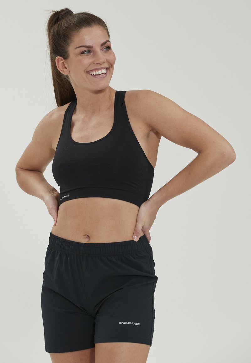 Sort atletisk bh og shorts sæt i et glat, strækbart materiale. Toppen har en racerback-design; shortsene har en elastisk talje.