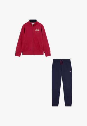 Sudadera roja con cremallera y bolsillos frontales; combinada con pantalones de chándal azul marino que tienen una cinturilla con cordón y detalle de logotipo.