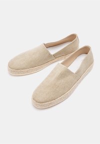 Beige Leinenschuhe im Espadrille-Stil mit einer geflochtenen Seilsohle und Slip-On-Design. Glatte Textur und minimalistischer Stil, geeignet für die Freizeit.