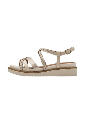 Beige wedge sandalen met gevlochten banden en een gestructureerde metalen accent. Voorzien van een gesp, platte zool en een zigzag profiel.