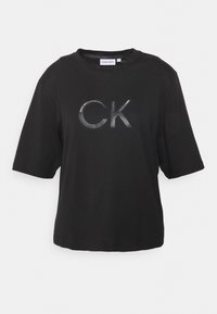 Sort bomulds T-shirt med korte ærmer, prydet med et skinnende "CK" logo på forsiden. Enkel rund halsudskæring, afslappet pasform og glat tekstur.