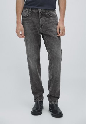 Svarta jeans av denim med en lätt blekt finish, femfickorsdesign och rak benpassform, tillsammans med svarta ankelstövlar.