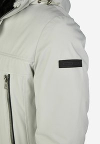 Lichtgrijze geïsoleerde jas met een ritssluiting op de borstzak, verstelbare capuchon, zwart label op de mouw, met gladde, gestructureerde stof.