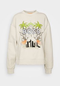 Krémová mikina s grafickým designem, na kterém jsou palmy a slovo „BOSS“ napsané tučnými písmeny. Hlavice rukávů je žebrovaná a má klasický design kulatého výstřihu.