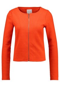 Oranssi lyhyt takki pitkillä hihoilla, teksturoidulla kuviolla, pyöreällä kaula-aukolla ja edessä vetoketjulla. Valmistettu paksusta, teksturoidusta kankaasta.