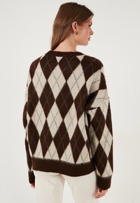 Pulover z rjavim in kremnim argyle vzorcem, debela pletenina, okrogli izrez, oversized kroj, rebrast rob in manšete.