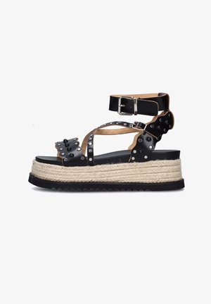 Sandali platform neri in pelle con suola in juta stile espadrille, dettagli con borchie, cinturino alla caviglia regolabile e design a incrocio.