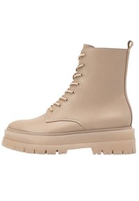 Bota de tobillo de cuero beige con cordones, suela de plataforma gruesa, acabado texturizado y ojales reforzados. Incluye una lengüeta en la parte trasera.