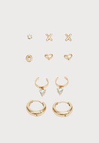 Conjunto de pendientes en tono dorado que presenta diversos diseños: pendientes de tipo stud en forma de estrella, cruz y corazón, y aros con piedras en forma de corazón.