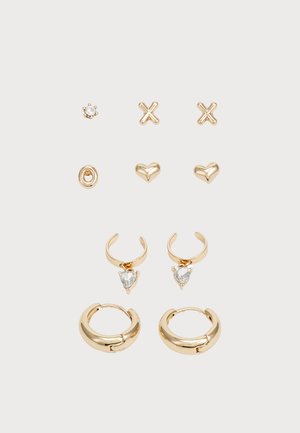 Set di orecchini in tonalità oro con vari design: orecchini a bottone a forma di stella, croce e cuore, e orecchini a cerchio con pietre a forma di cuore.