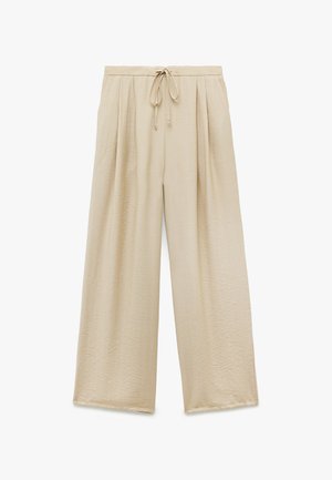 Beige, wijde broek met een textuurstof, voorzien van een trekkoord in de taille en geplooide voorkant. Geen zakken of extra hardware.