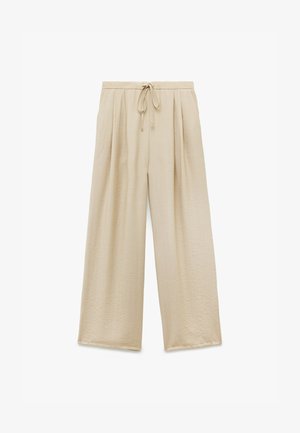 Pantaloni beige a gamba larga in tessuto texture, con cintura elastica regolabile e pieghe frontali. Senza tasche né ulteriori accessori.