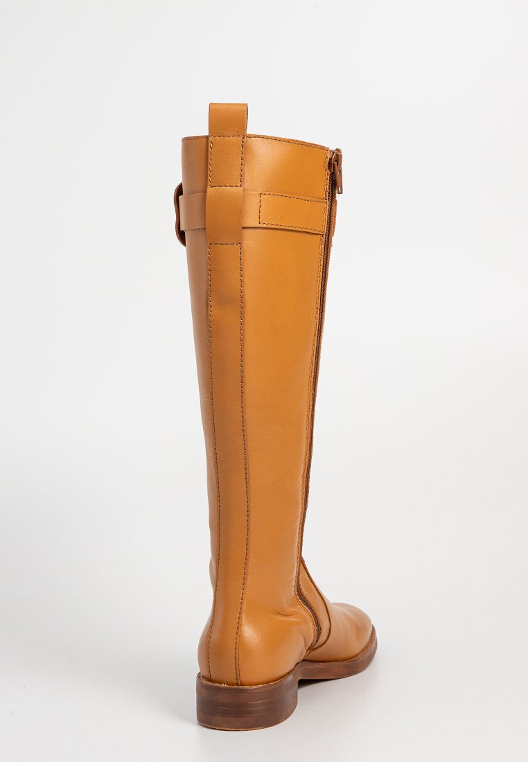 Hoge, bruinleren laars met een gladde textuur, ronde neus en een houten hak. Voorzien van een rits aan de achterkant en een lus aan de bovenkant voor eenvoudig aantrekken.