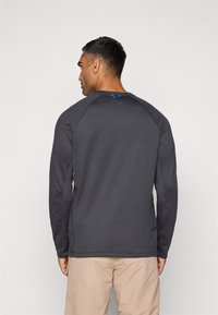 Dunkelgraues Langarmshirt mit Rundhalsausschnitt, Raglanärmeln und einem kleinen blauen Akzent am Rücken des Halsausschnitts. Angenehme Textur.