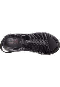 Černé kožené boty s otevřeným designem, které mají více pletených pásků, plochou podrážku a nastavitelný pásek kolem kotníku pro bezpečné uchycení.