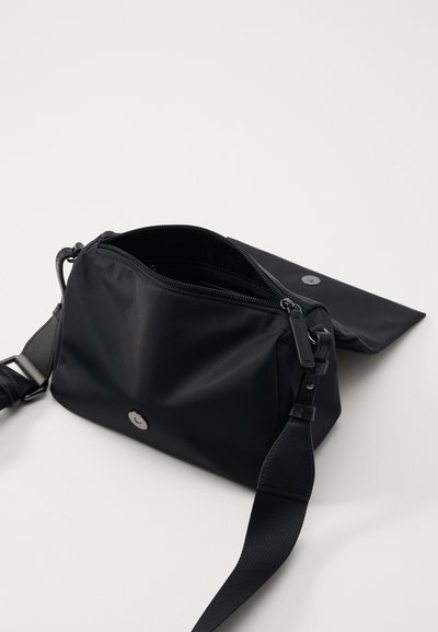 Czarna nylonowa torba na ramię z zamykanym głównym kompartamentem, regulowanym paskiem i zapięciem na zatrzask. Gładka faktura, minimalistyczny design.