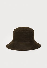 Bruine corduroy emmerpet met een zachte textuur, brede rand en verticale ribbelpatroon, die een gestructureerd maar ontspannen ontwerp laat zien.