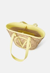 Vävd stråväska i beige med ett klart gult läderinteriör och handtag. Har en stor logotyp och ett inre dragkedjefack.