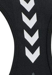 Schwarzer Stoff mit fünf weißen Chevron-Pfeilen, die nach unten zeigen, in einer vertikalen Linie, detailliert mit sichtbaren Nähten entlang der gebogenen Kanten.